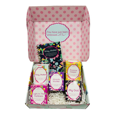 Box of assorted Christian cnadles and notebook with colorful packaging on a white background